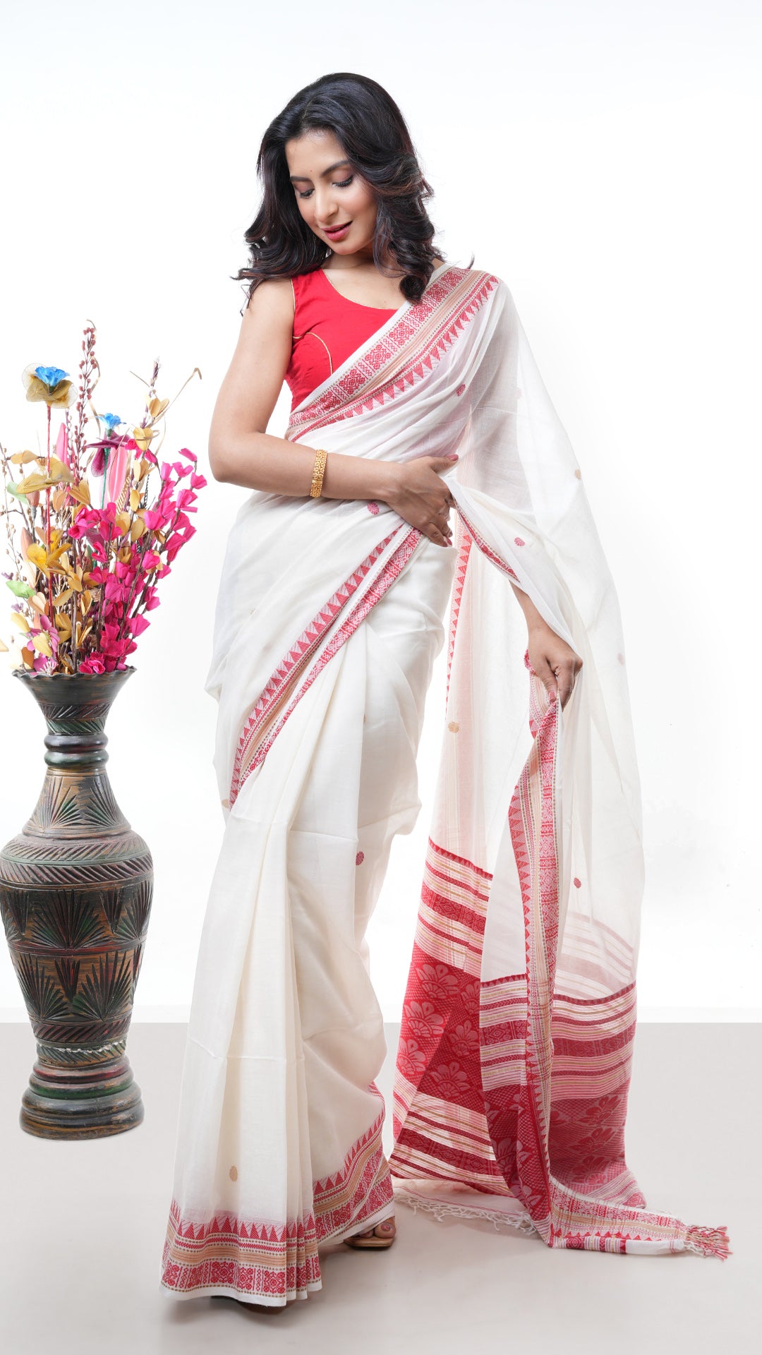 An off white red cotton saree. An off white red soft cotton cotton saree. The pallu has stripe details. Crafted with soft cotton Warp and weft. Standard 5.5-meter length. Includes matching blouse piece. Tangail saree, cotton saree.