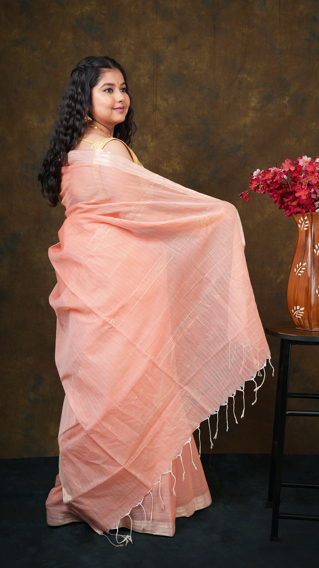 A bright peach coloured tangail saree