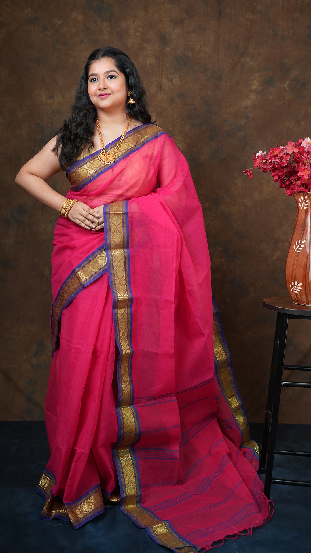 Dark rani tangail saree with blue, green, and golden zari border. Plain body with vertical striped pallu. 5.5 meters
