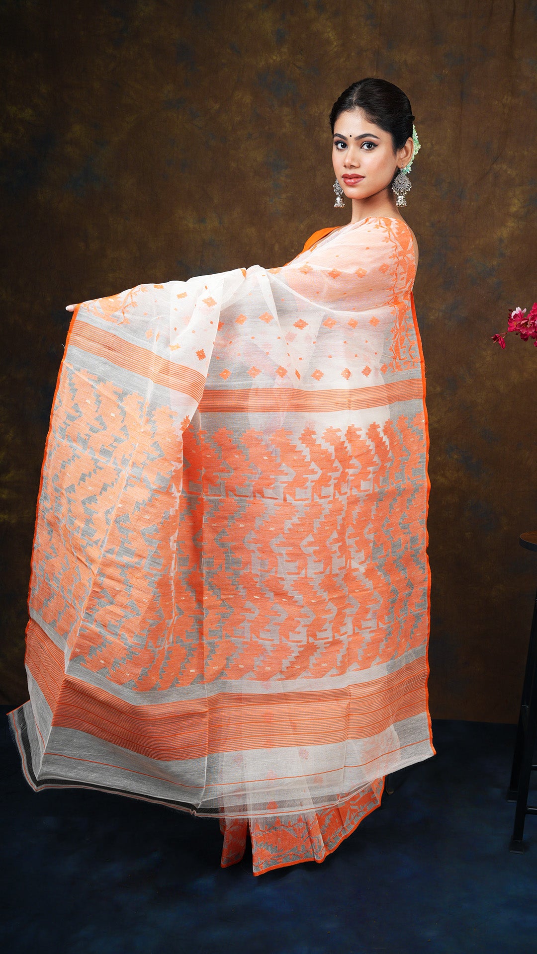 An off white and orange jamdani saree