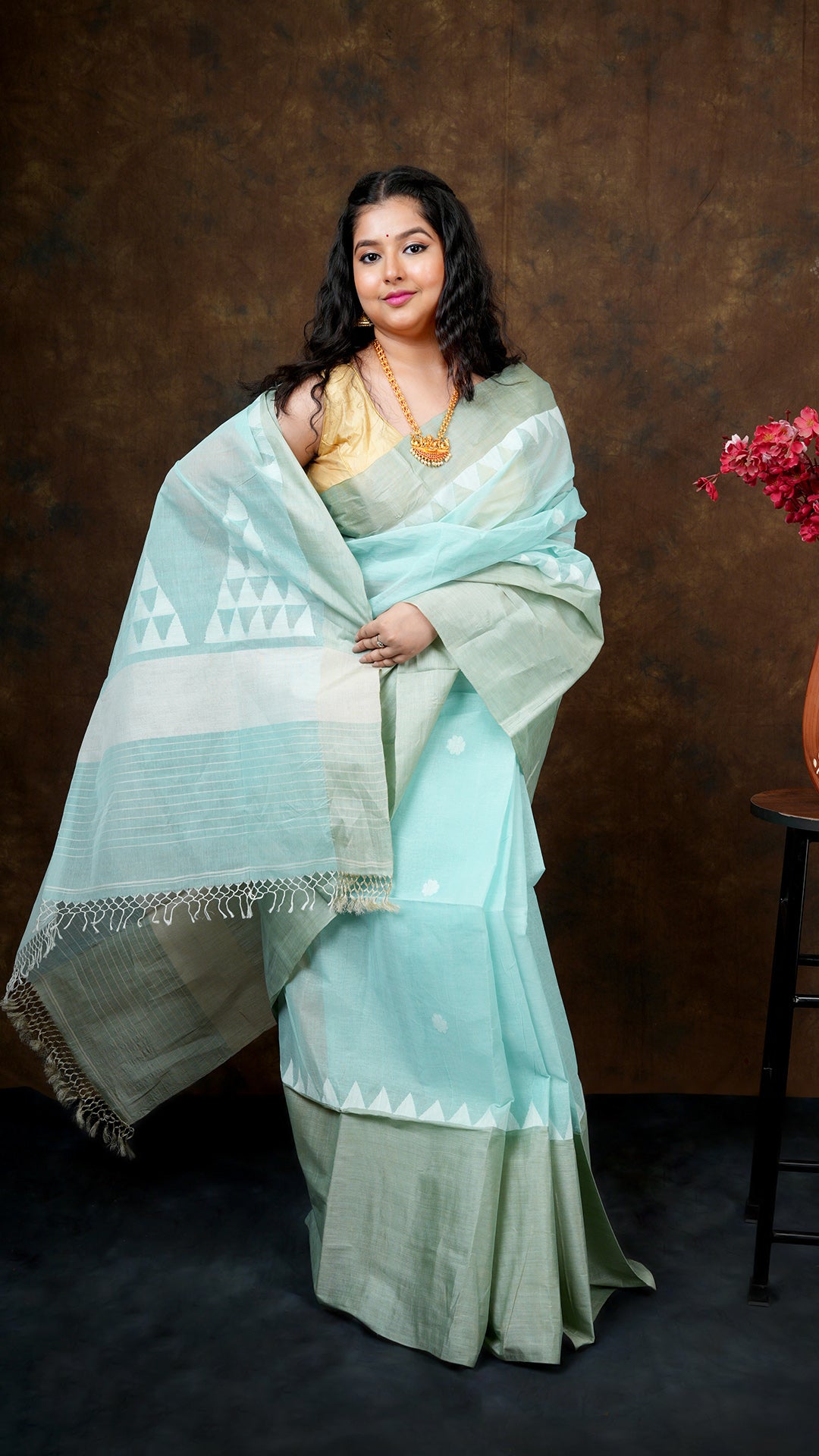Light firozi tangail saree with broad and narrow tassar borders. Butis and pallu woven in white. Includes 0.8m running blouse. 5.5 meters.