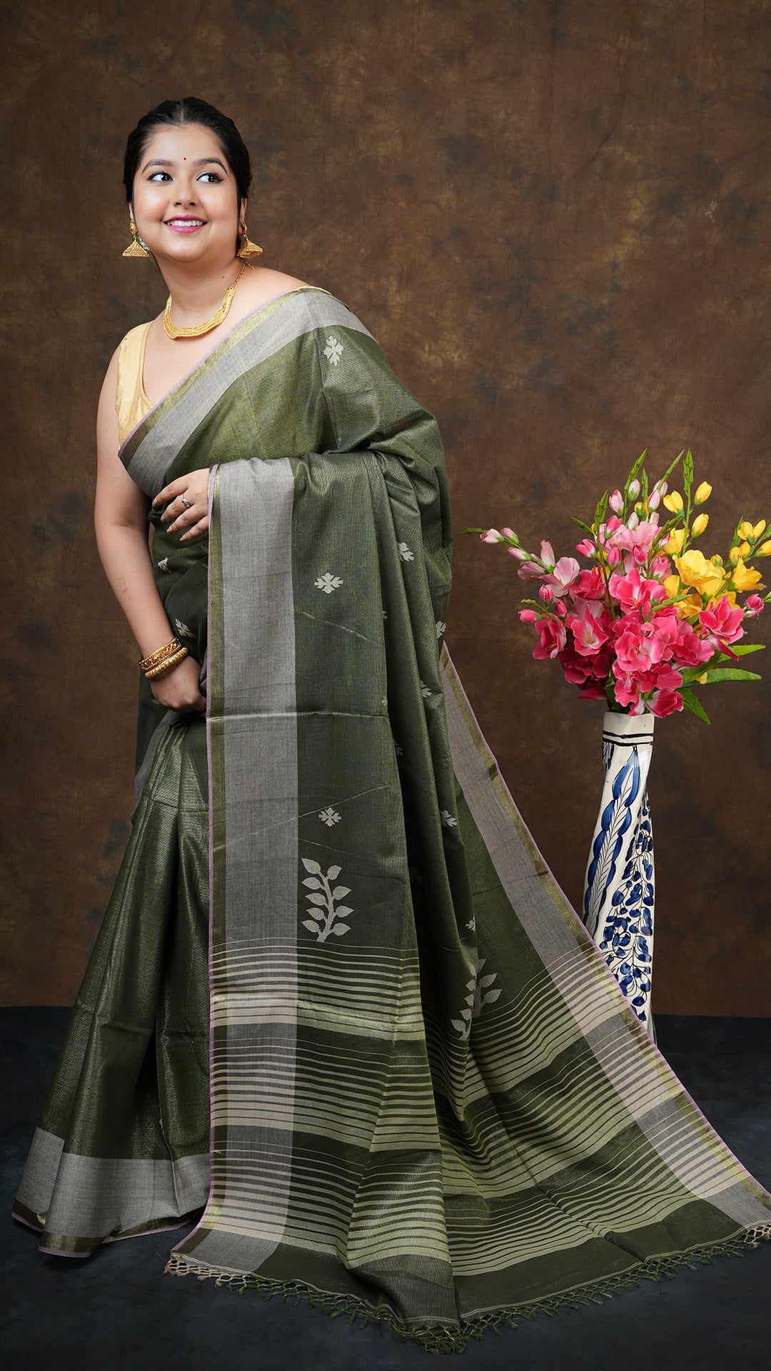 Blackish green tissue saree with golden zari, off-white/pink border, and off-white butis/pallu. Includes 0.8m running blouse. 5.5 meter tangail weave
