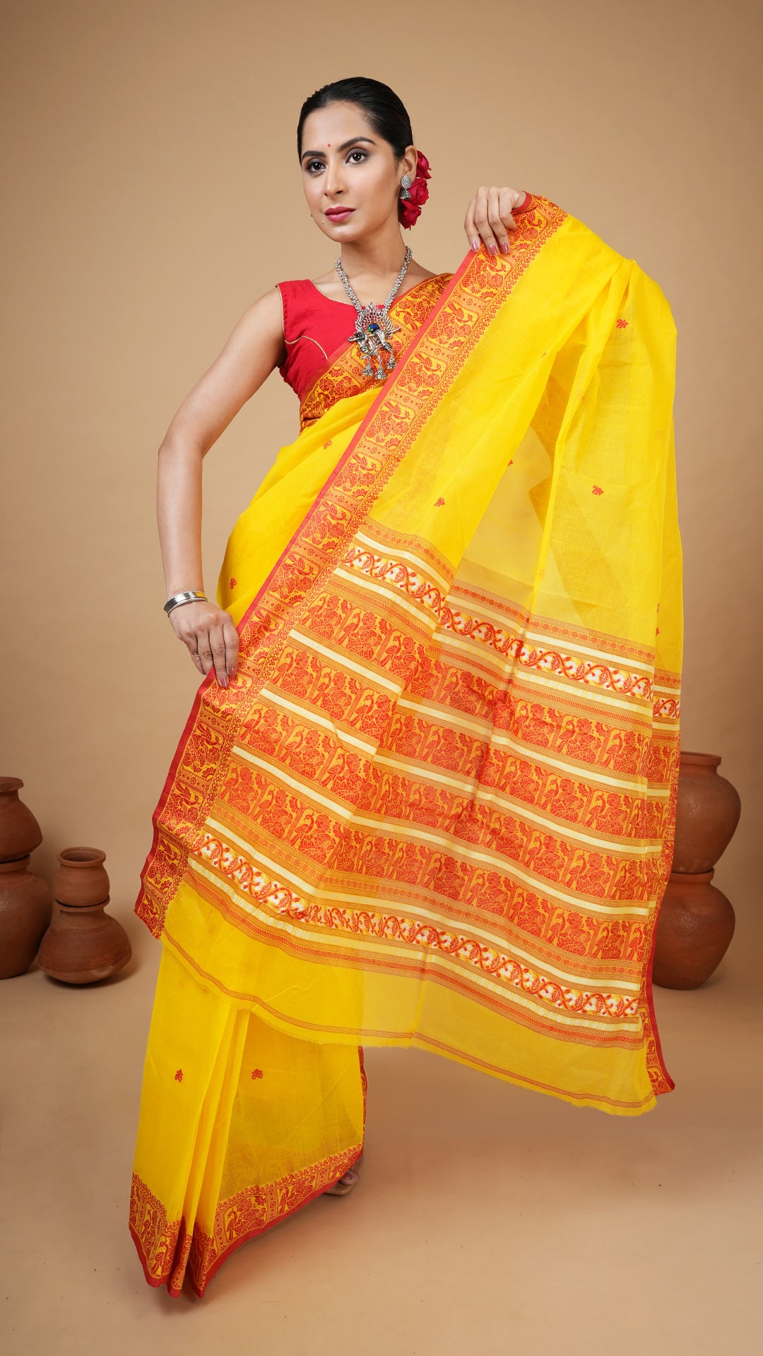 Bright yellow cotton baluchari saree with red and white motifs on border, butis and pallu. Traditional wedding saree for gaye holud.