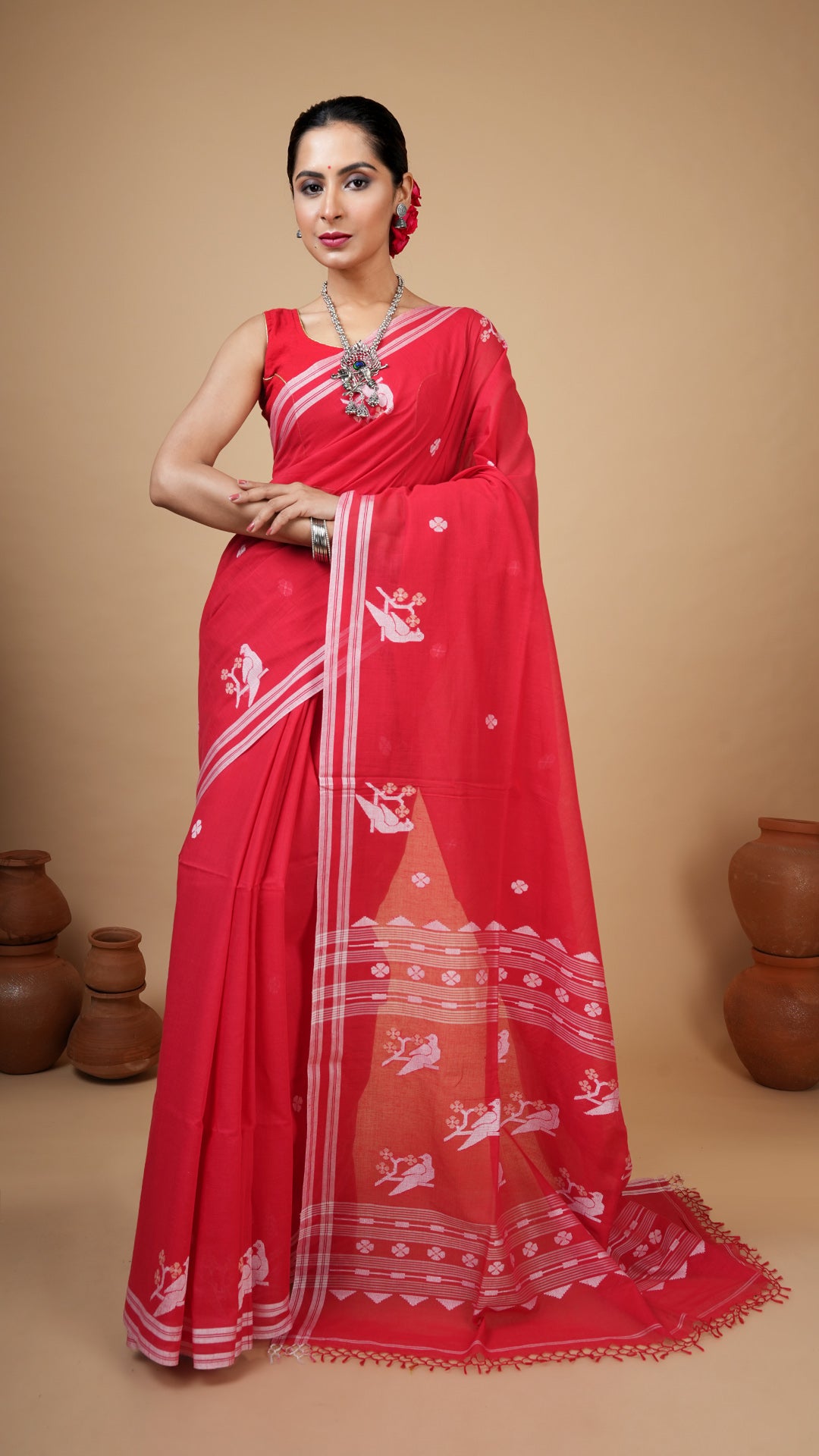 Woman wearing a red saree with white patterns on a beige background