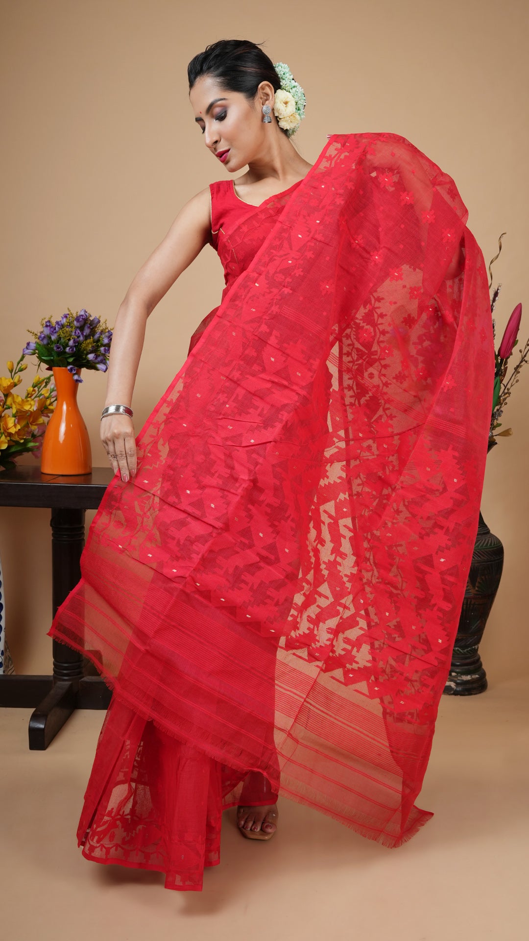 Red cotton jamdani saree with self-colored weave and golden zari highlights on butis, border and pallu. Classic festive saree.