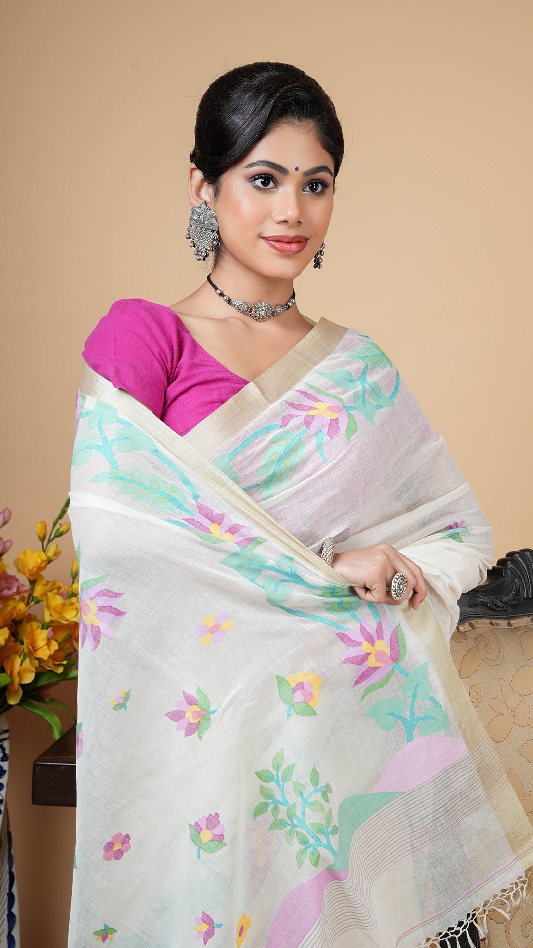 Off-white Dhakai soft cotton saree with flat tassar border and multicolor woven motifs in green, lavender, magenta, yellow, and pink. Elegant choice for parties, pujas, or gifting.