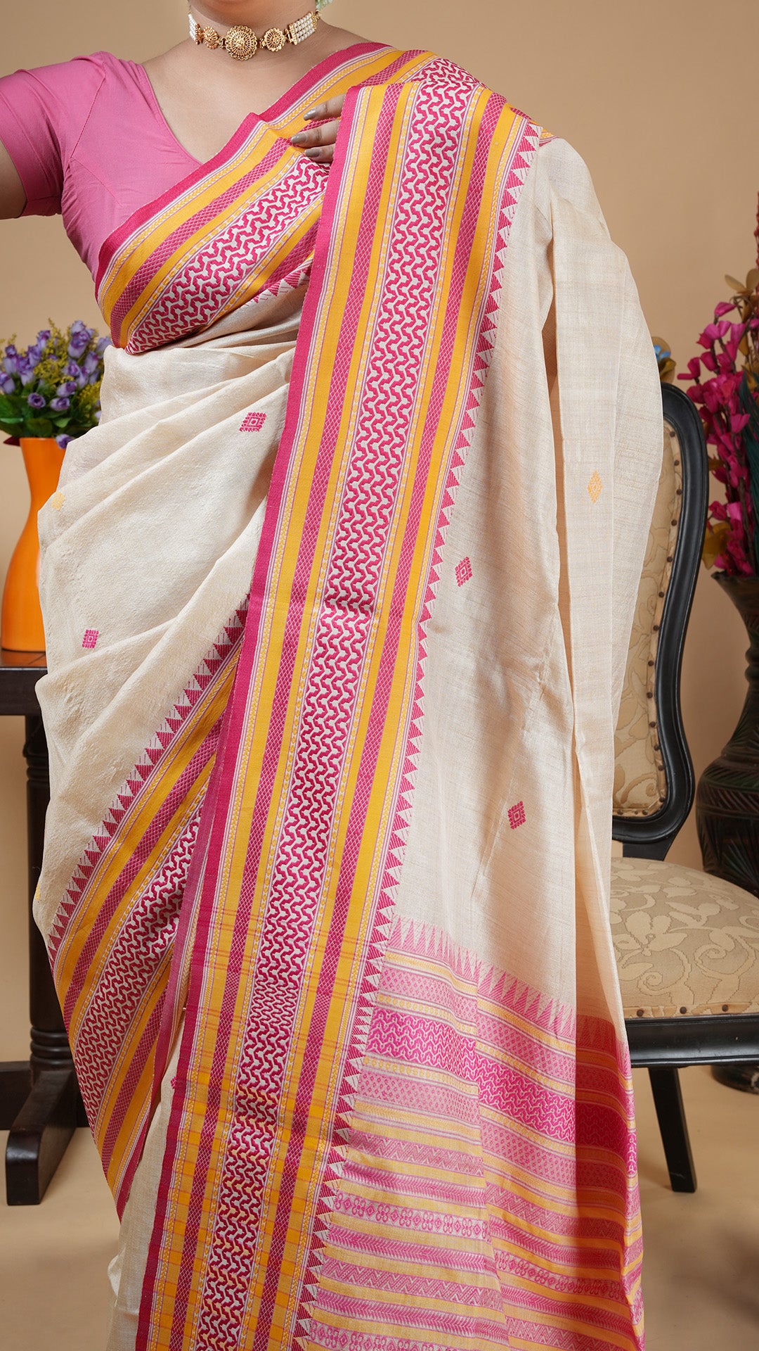 Tassar saree with pink and yellow border, butis, and pallu. Subtle yet festive attire for puja or wedding functions.