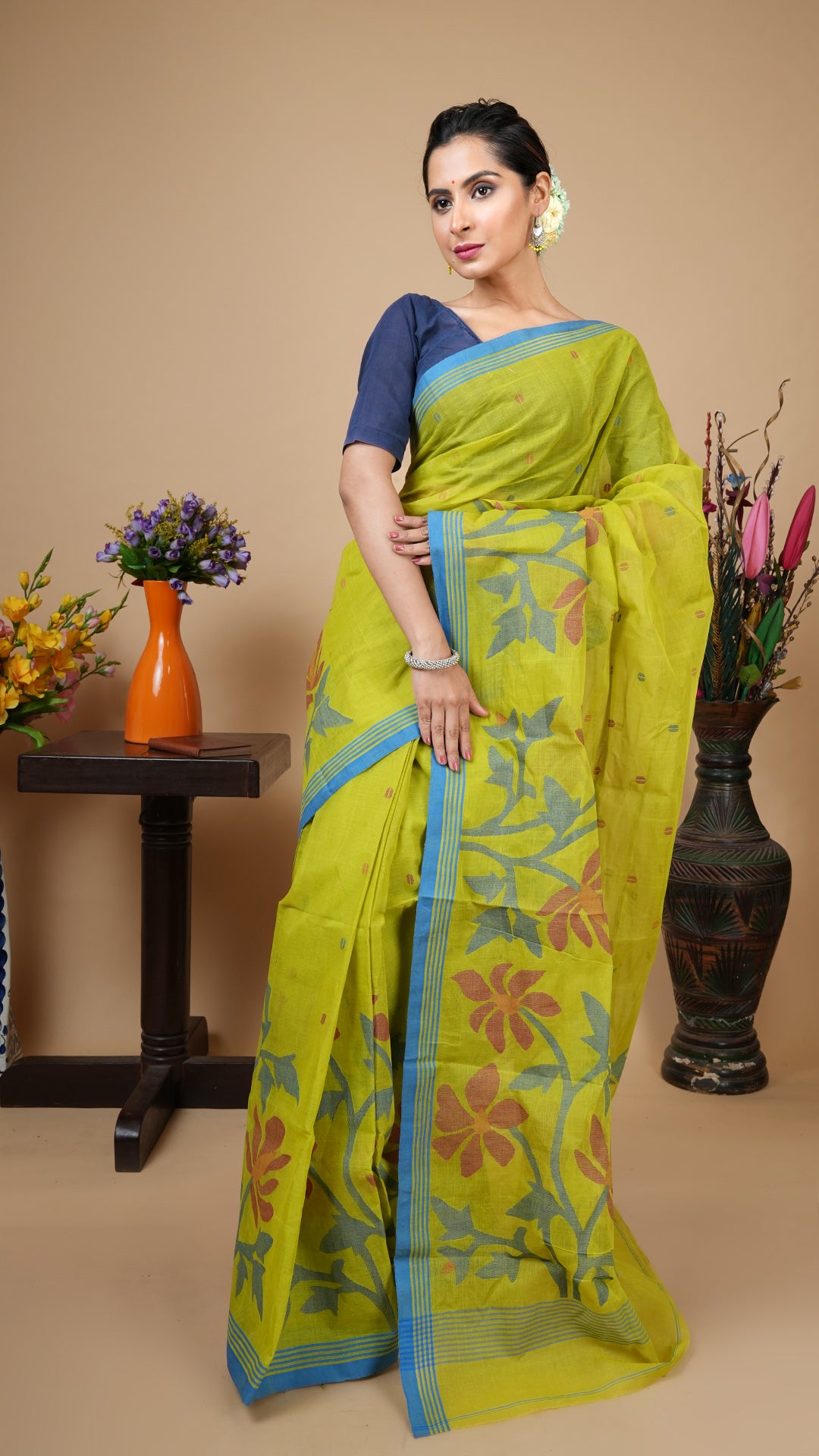 Green cotton Dhakai saree with broad lower border in blue, orange, and maroon, striped upper border, and woven butis and pallu in matching colours. Elegant festive piece.