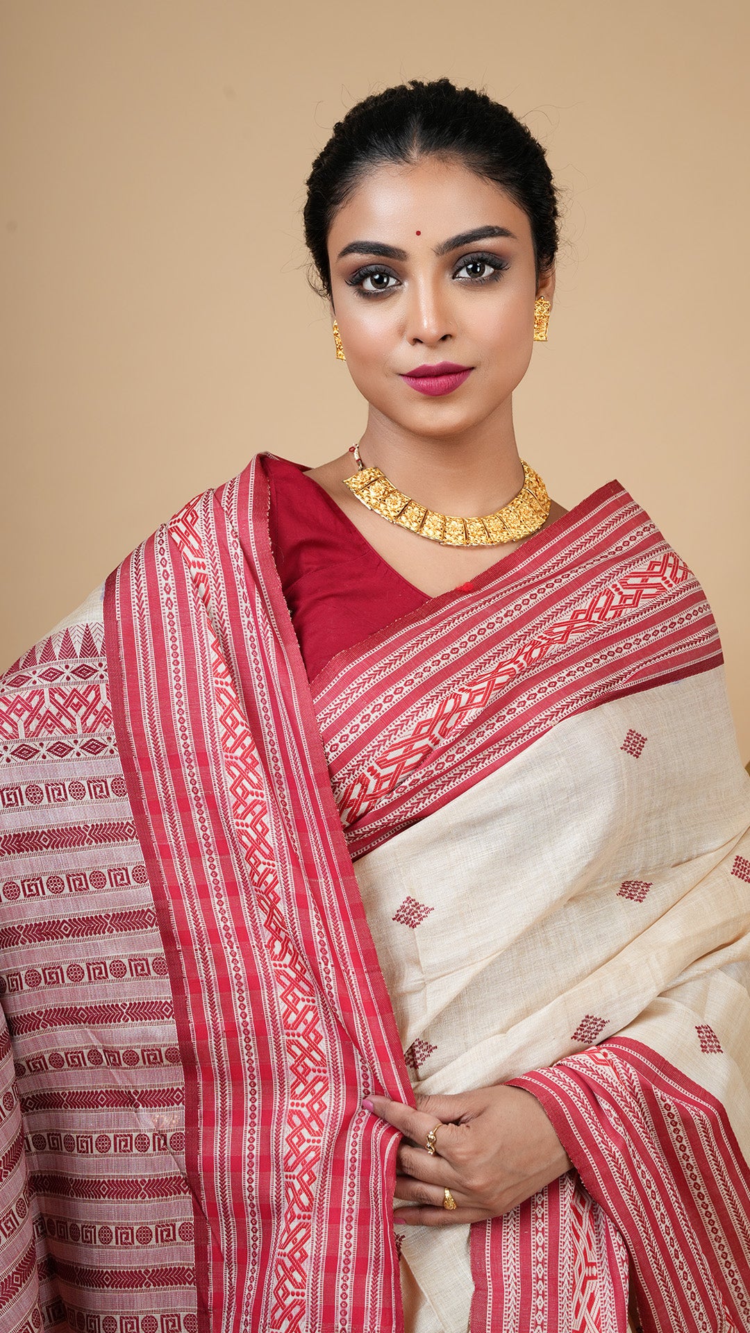 Close-up of tassar saree in red and maroon Tangail weave, showcasing fine fabric texture, intricate border patterns and elegant traditional styling