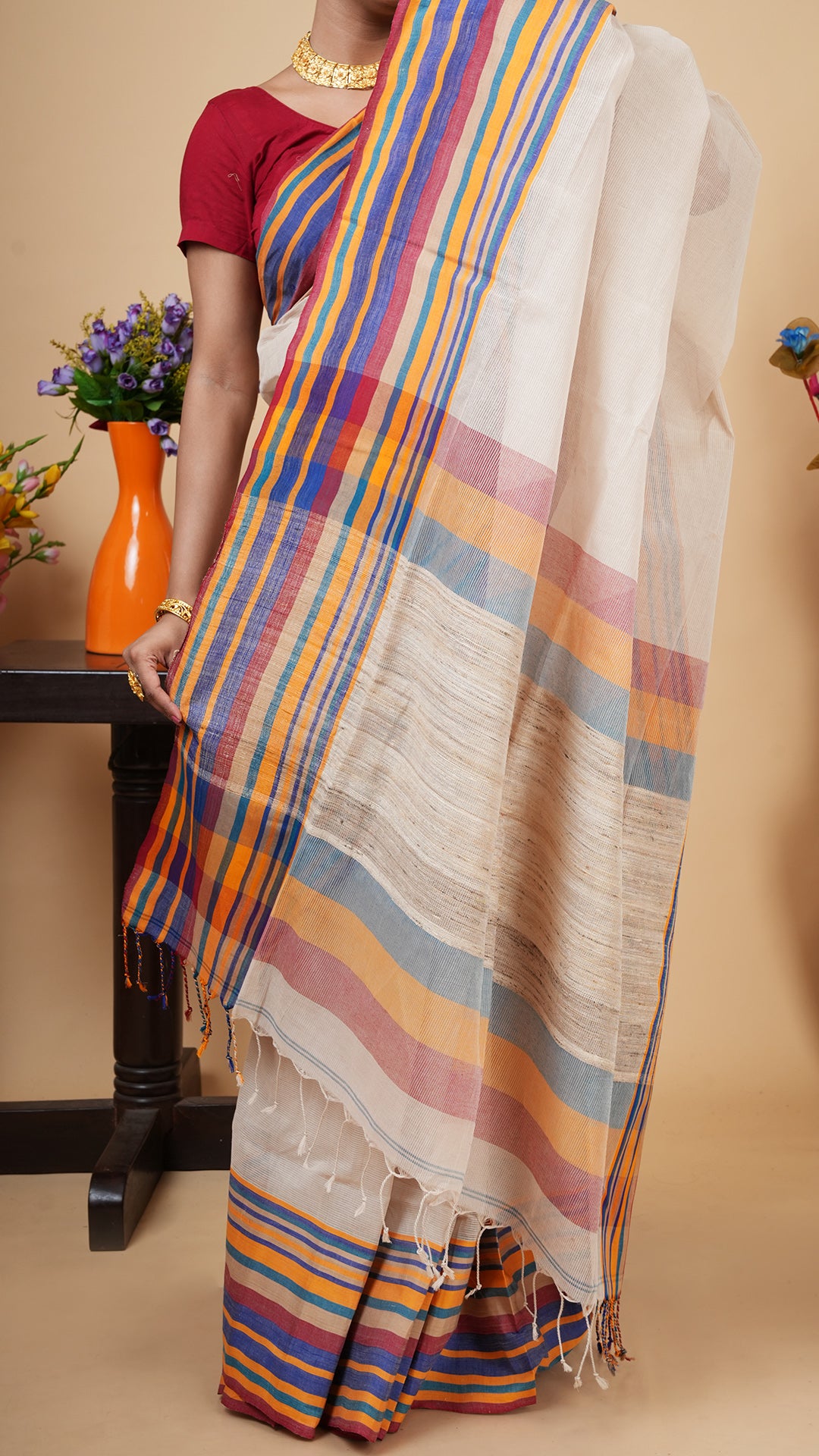 Close-up of a light beige cotton saree pallu featuring bold blue, orange, and maroon stripes with a visible self-stripe weave.