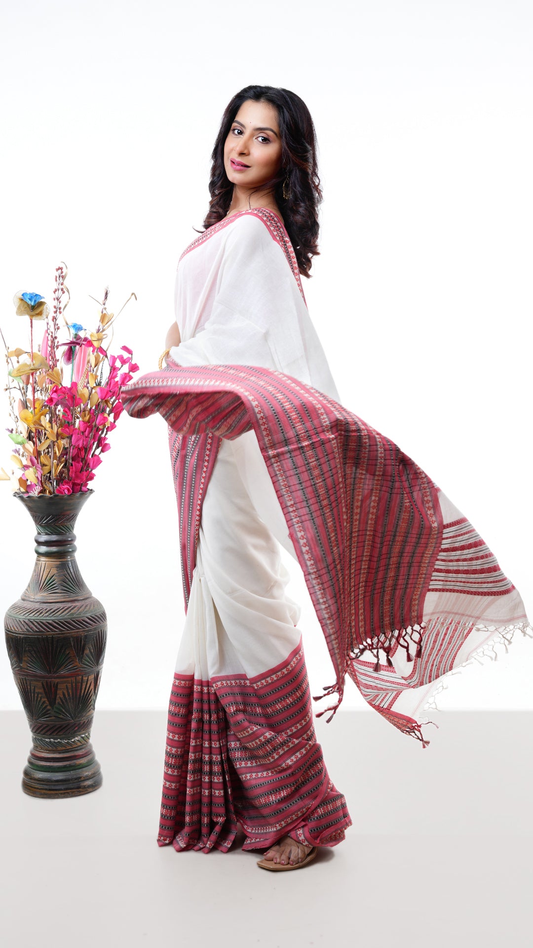 An off white broad border saree. An office soft cotton cotton saree with red and black contrast. The border is striking. Crafted with soft cotton Warp and weft. Standard 5.5-meter length. Includes matching blouse piece. Tangail saree, cotton saree.