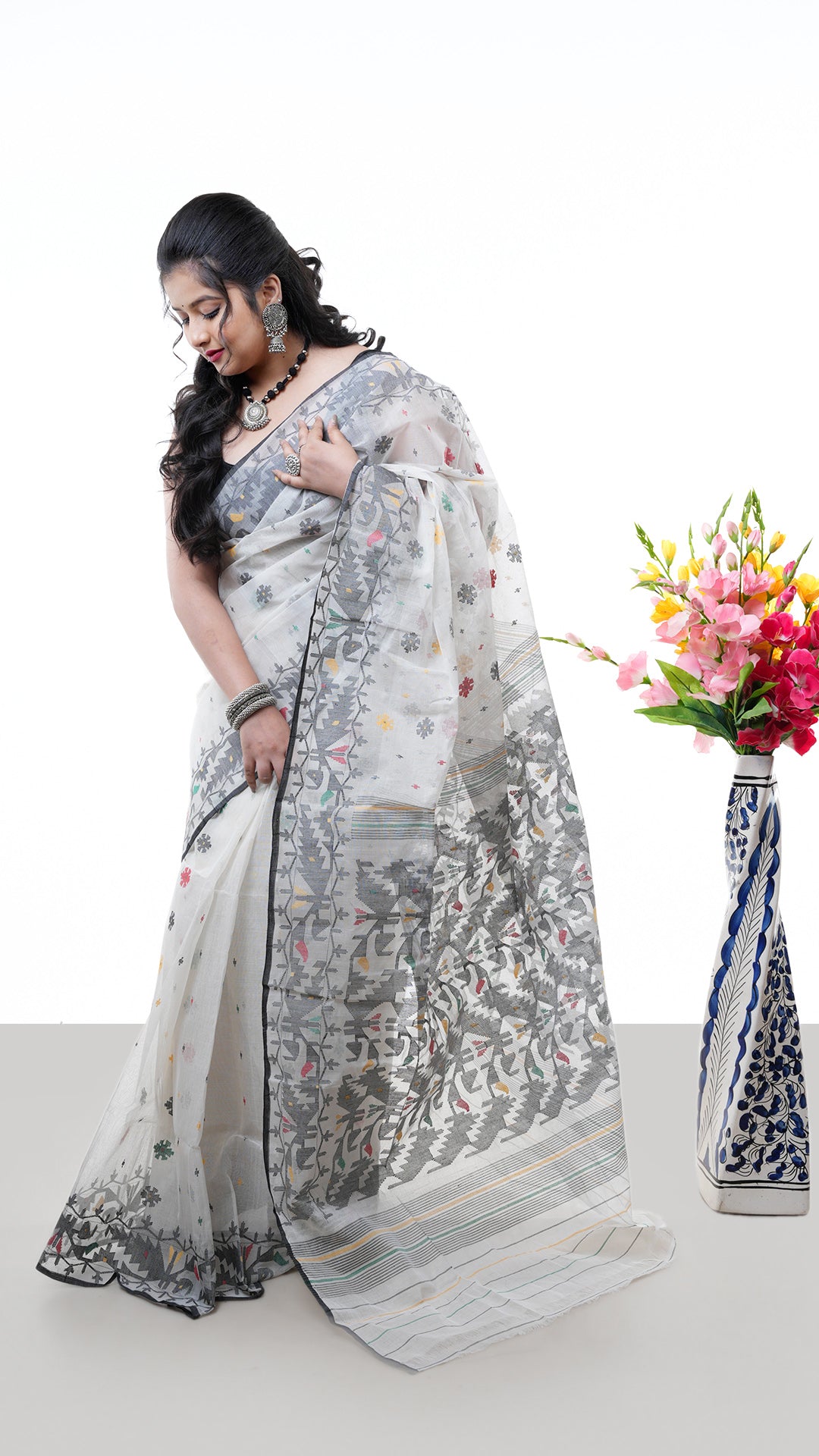 A multi coloured jamdani saree. An off white jamdani sari with colourful floral thread weave. Crafted with cotton Warp and weft. Standard 5.5-meter length. Includes matching blouse piece. cotton saree
