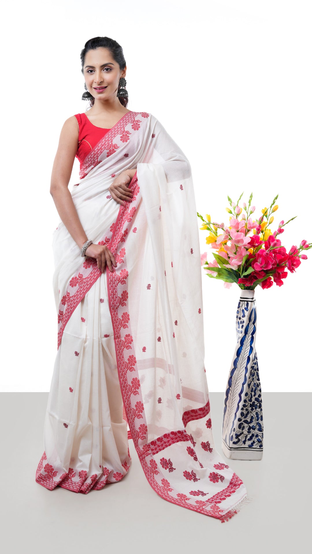 An off white and red Tangail saree. A Tangail saree with soft texture and traditional look. Crafted with soft cotton Warp and weft. Standard 5.5-meter length. Includes matching blouse piece. Tangail saree, cotton saree