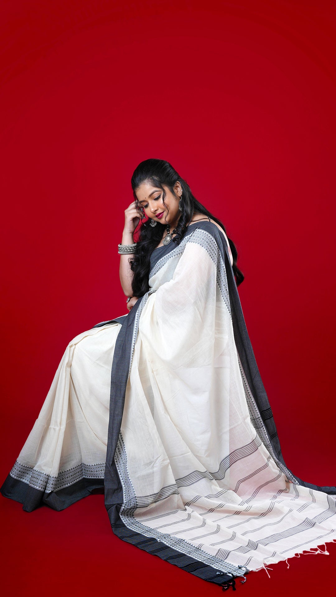 An off white and black Tangail saree. An off white body with black accent border and rich pallu. Crafted with soft cotton Warp and weft. Standard 5.5-meter length. Includes matching blouse piece. Tangail saree, cotton saree