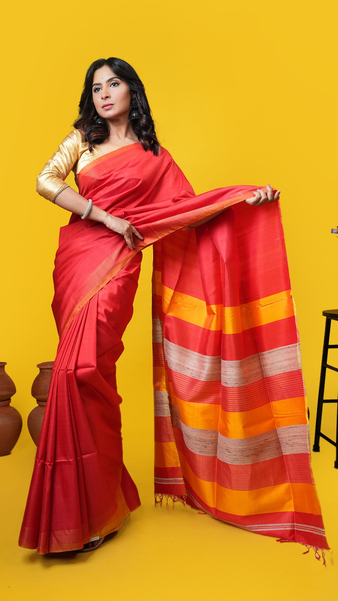 Vermillion silk Tangail saree with golden zari striped border, plain body, and zari-yellow-jute pallu. Price: Rs. 6,500/-