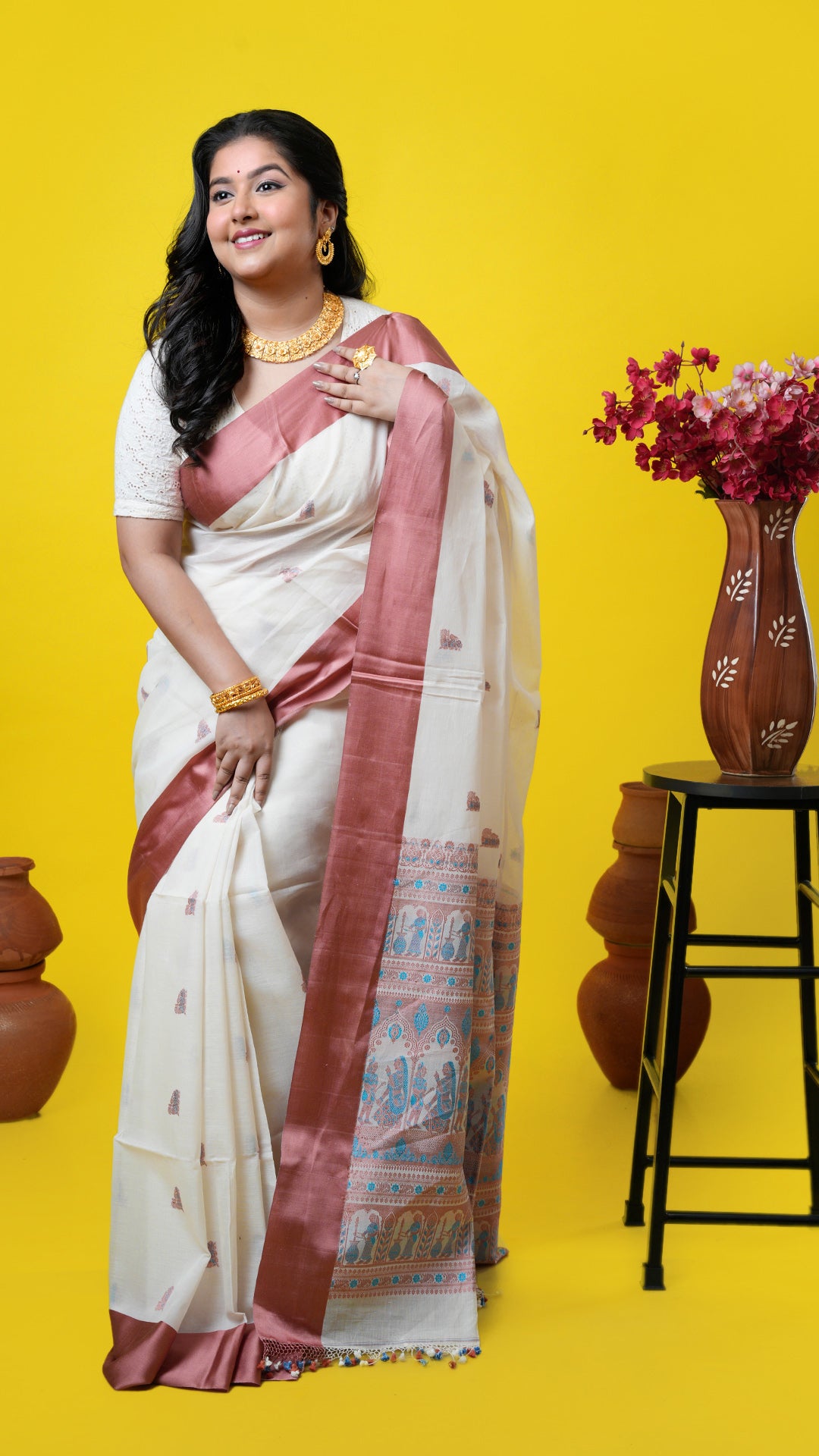 Off-white soft cotton saree with cinnamon satin border, Baluchari motifs in cinnamon and ferozi. Price: Rs. 15000/-