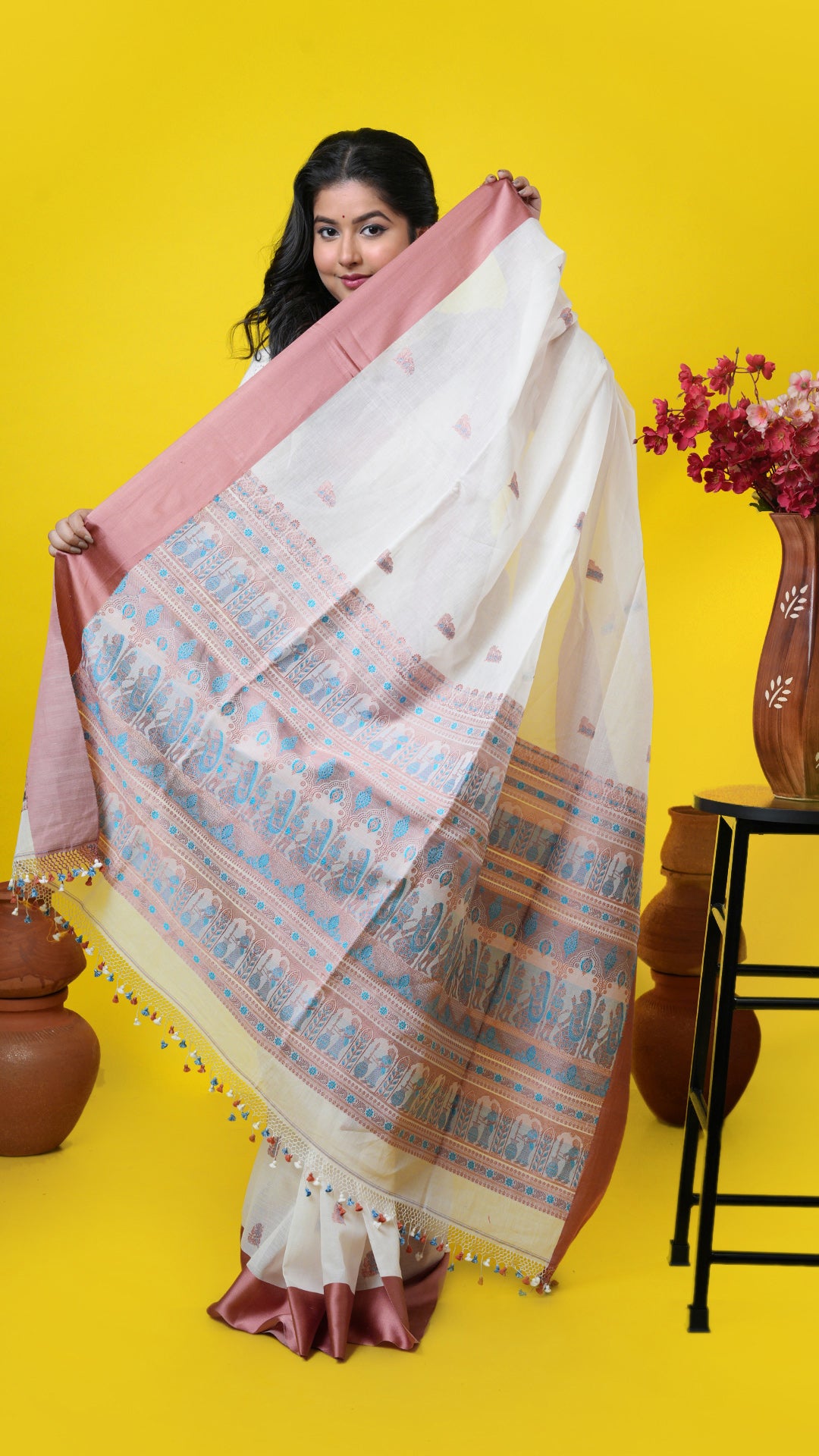 An off white and cinnamon coloured saree