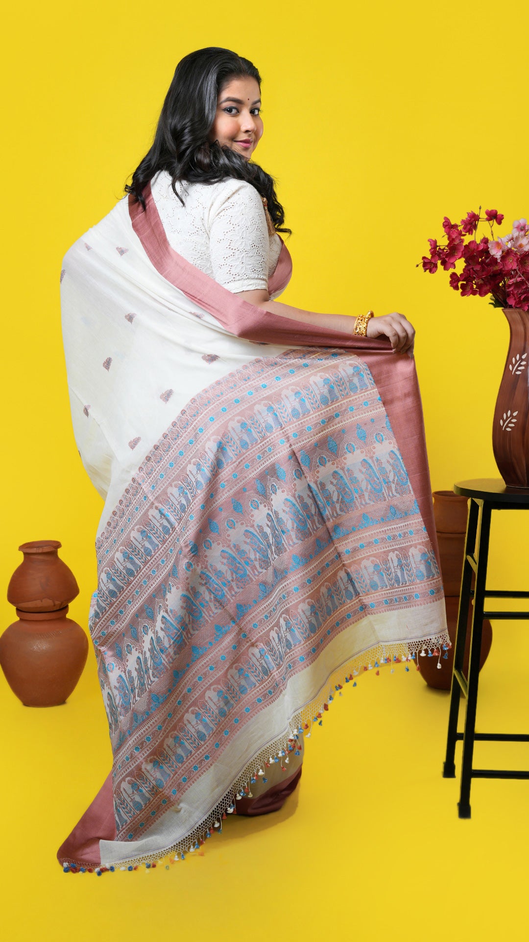 An off white and cinnamon coloured saree