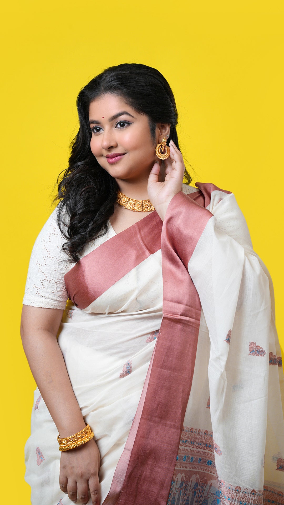 An off white and cinnamon coloured saree