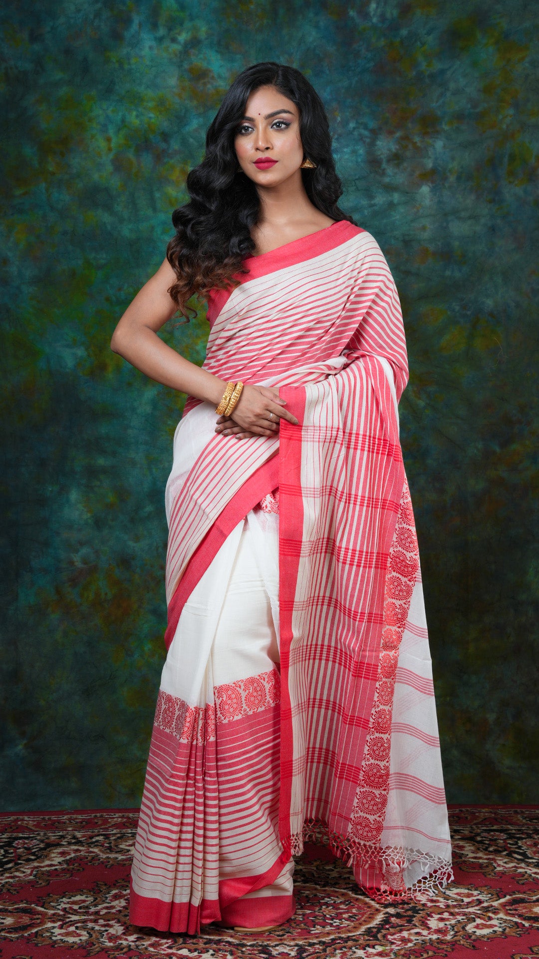 Off-white soft cotton Tangail saree with red woven border in uneven horizontal stripes and vertical striped pallu. No butis. Price: Rs. 1900/-