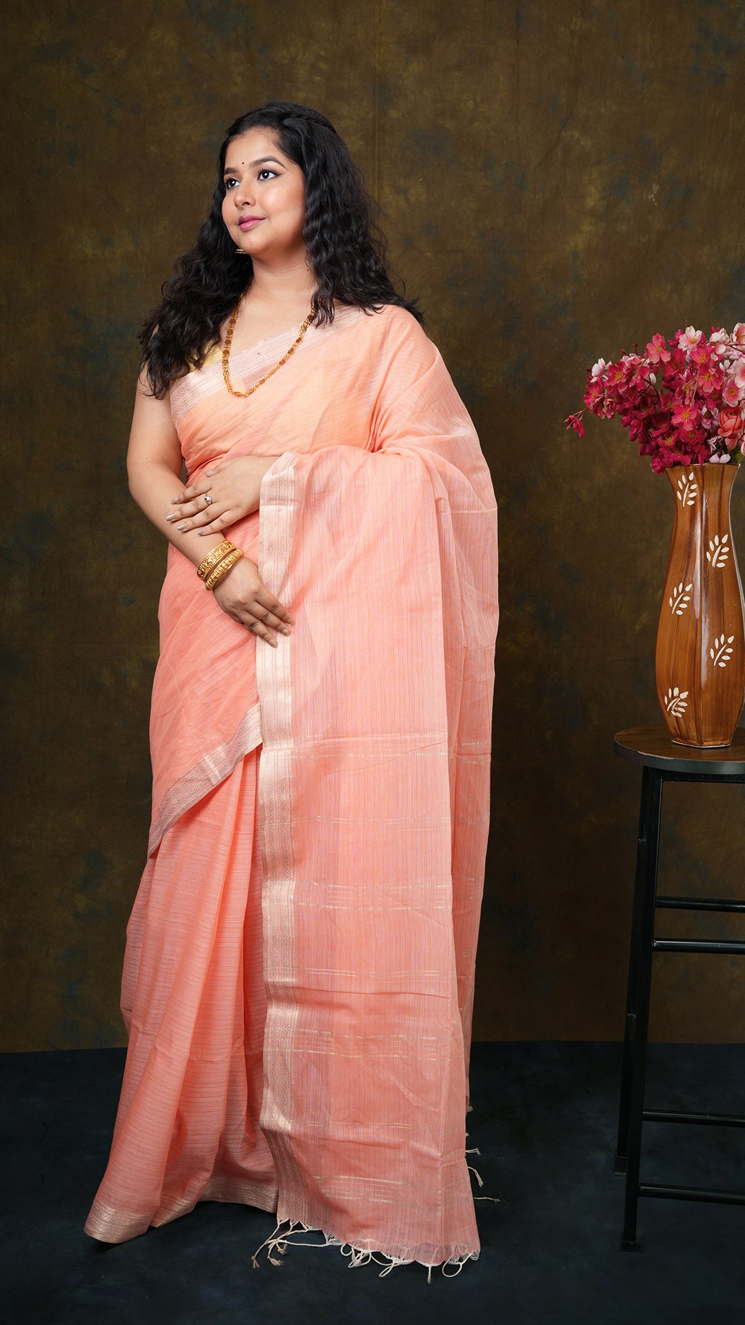 Bright peach soft cotton tangail saree with golden zari border and vertical striped pallu. No blouse piece. 5.5 meters.