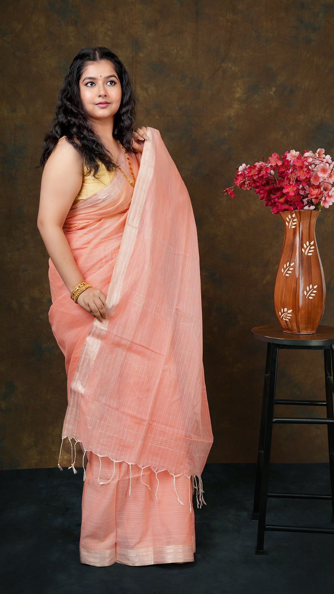 A bright peach coloured tangail saree
