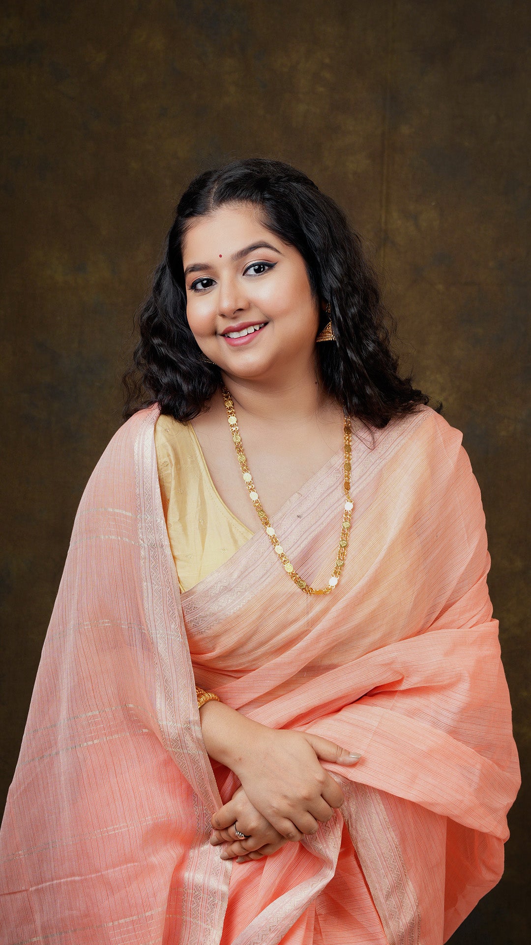 A bright peach coloured tangail saree