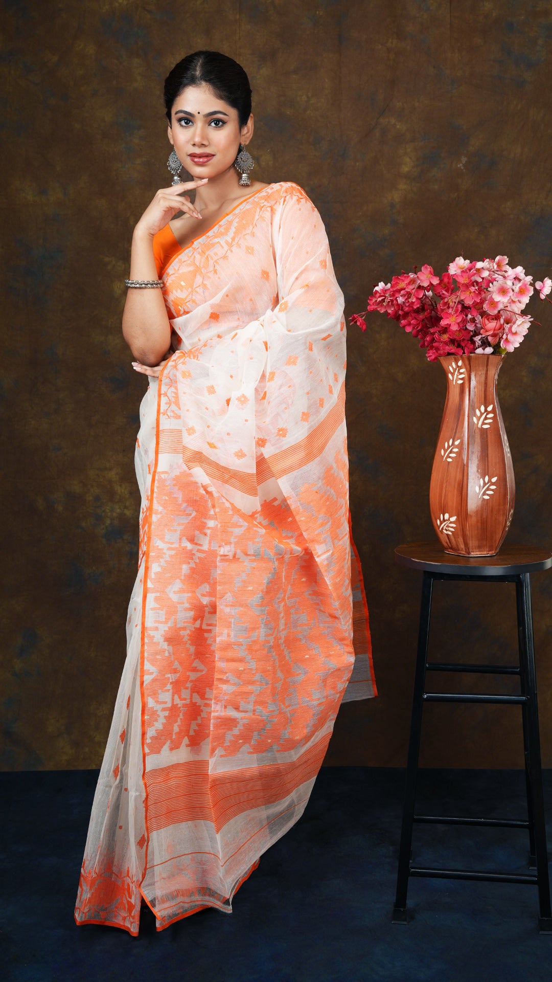 Off white muslin jamdani saree with orange and golden zari border, butis, and pallu. No blouse piece. 5.5 meters.