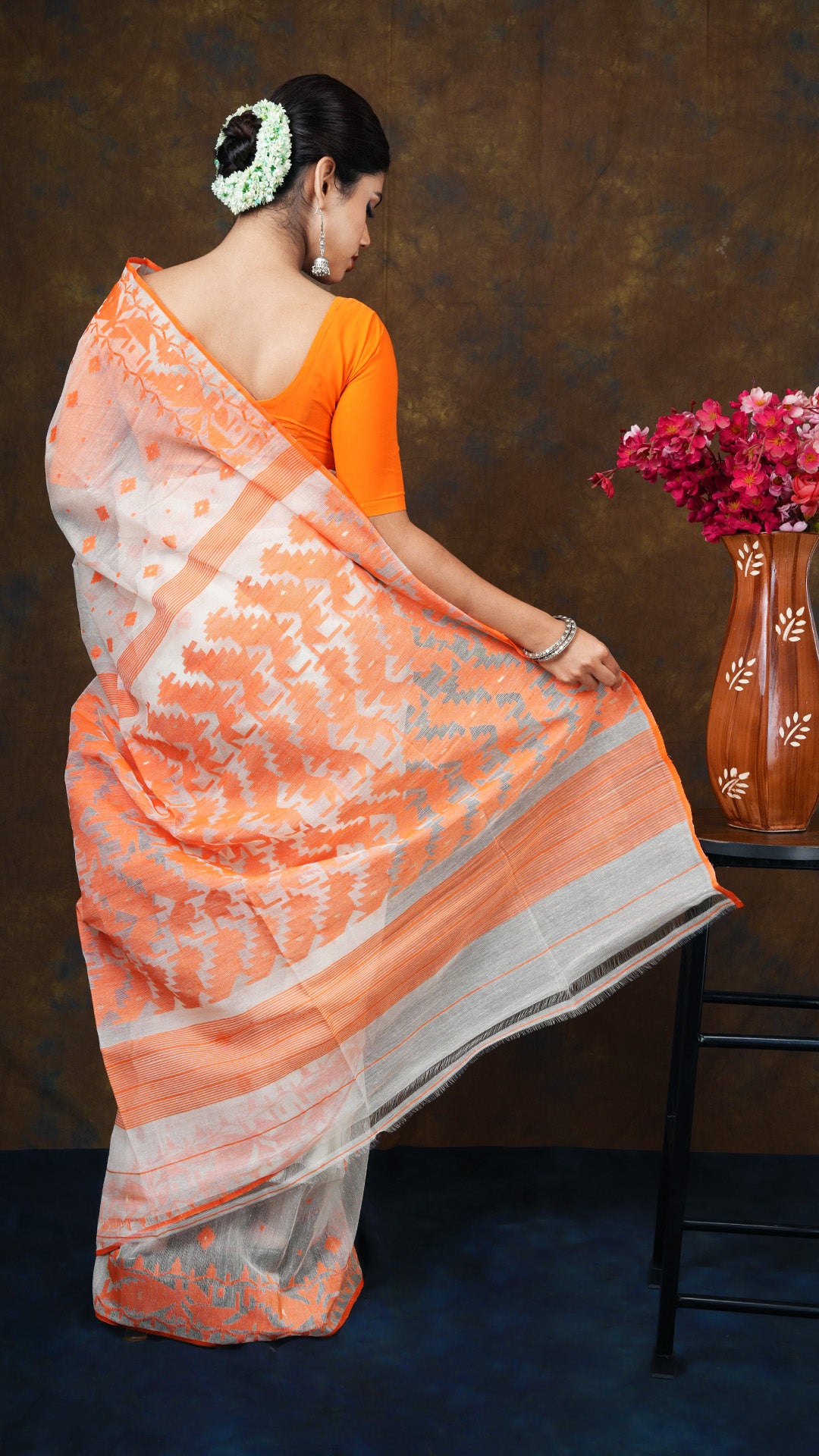 An off white and orange jamdani saree