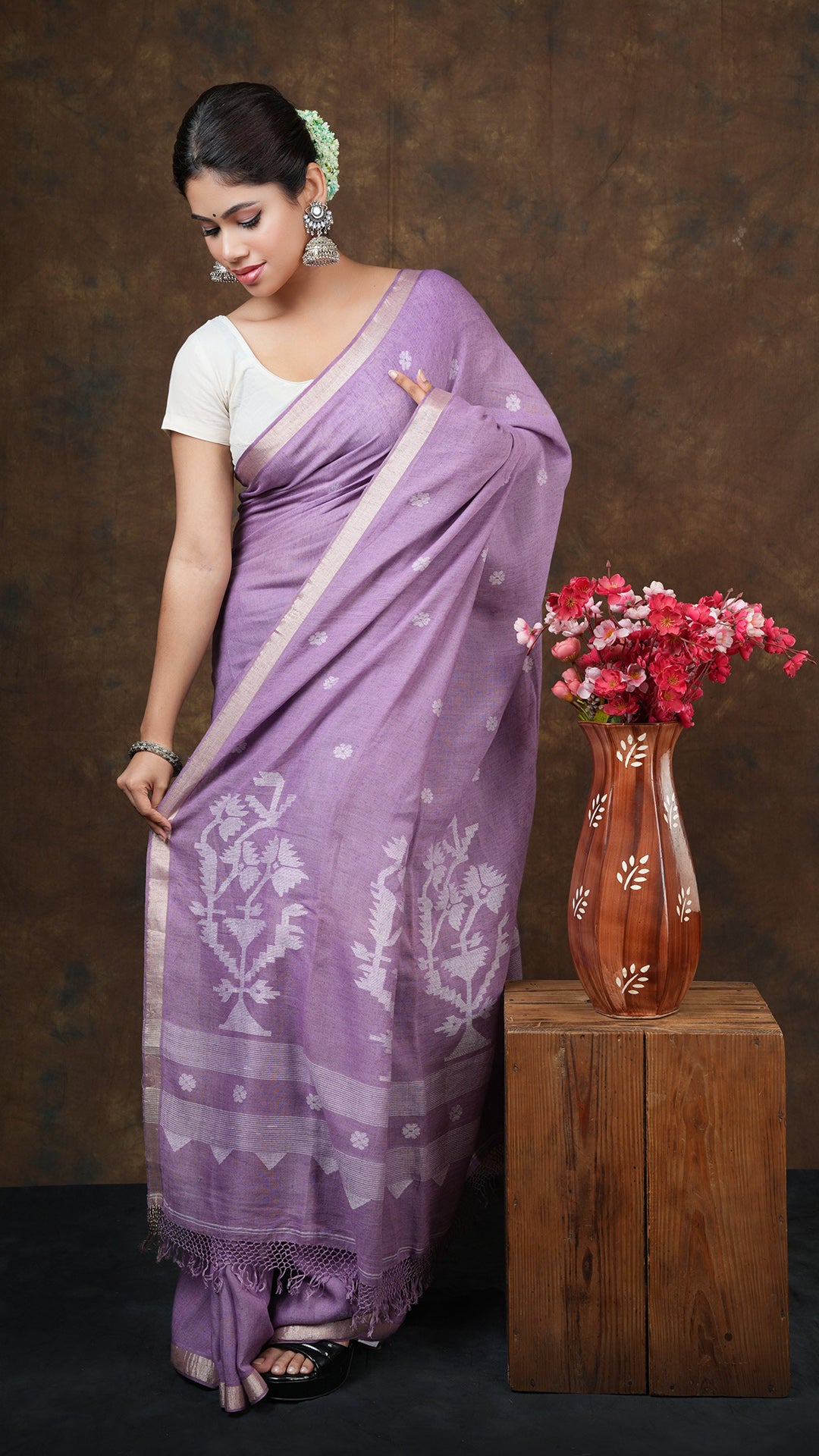 A mauve linen saree - A soft linen saree in mauve with golden borders and white woven butis and pallu. This elegant Linen saree, Dhakai saree is perfect for subtle traditional styling.