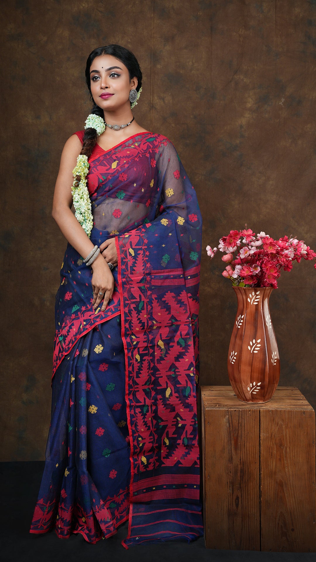 A navy blue multicolored jamdani - A navy blue muslin silk saree with traditional multicolor weaving on the butis, border and pallu. This elegant Jamdani saree, Dhakai saree is ideal for cultural occasions.