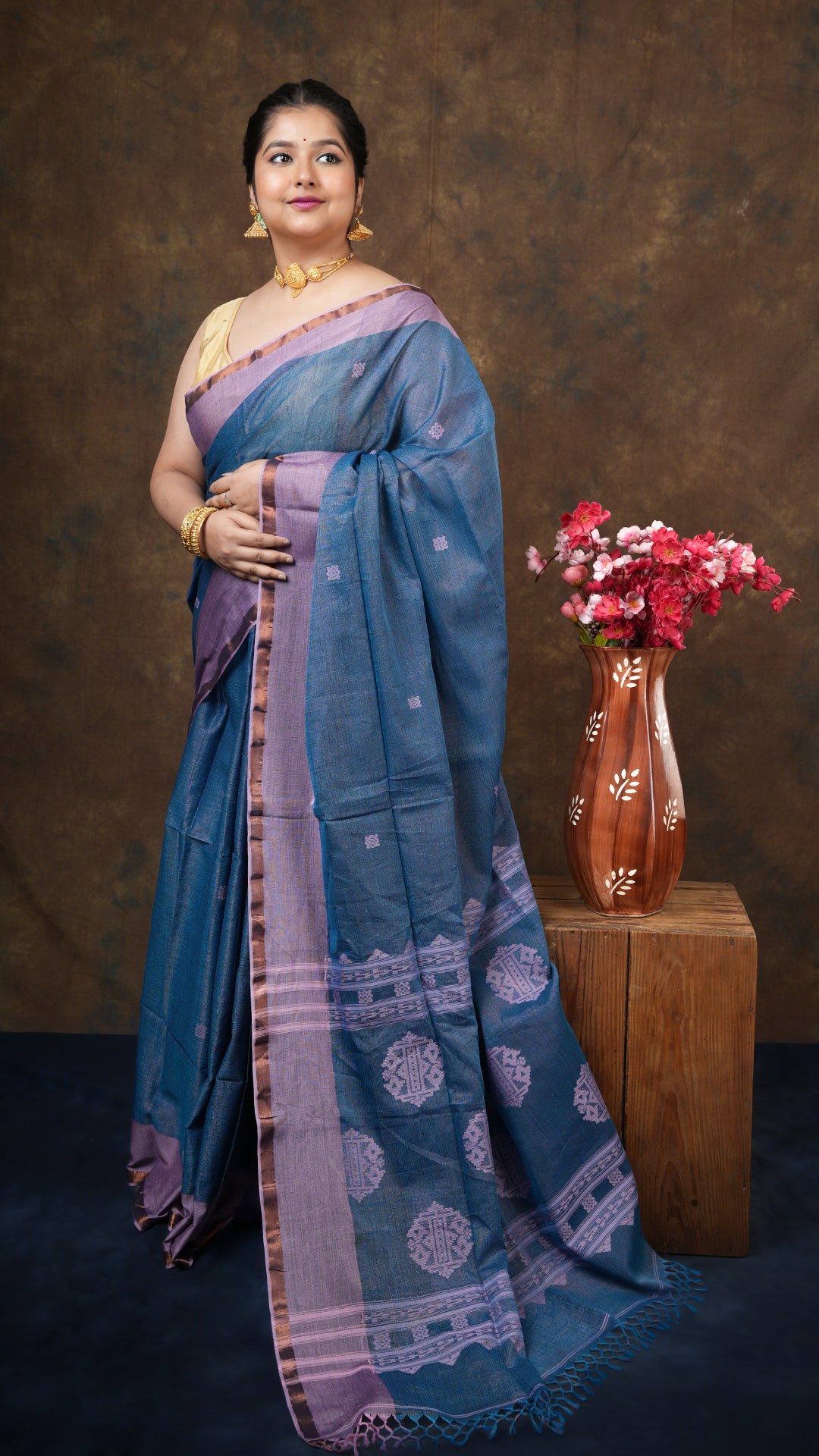 A blue tangail tissue saree - A soft cotton blue tissue saree with zari body, pink borders, and butis. This shimmering Tangail saree is a great festive wear.