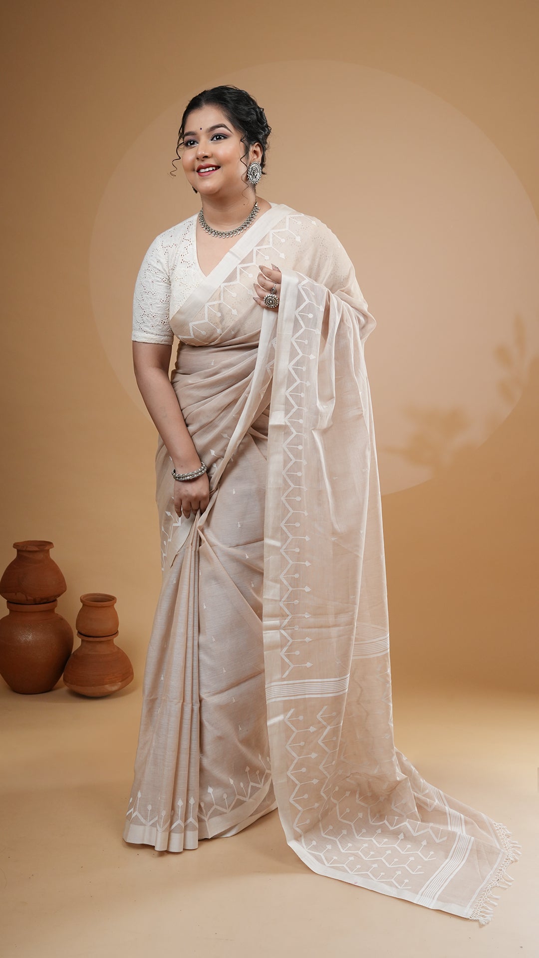 Fawn soft cotton dhakai saree with off-white woven butis, border, and pallu. Ideal for daily office wear and traditional gatherings.