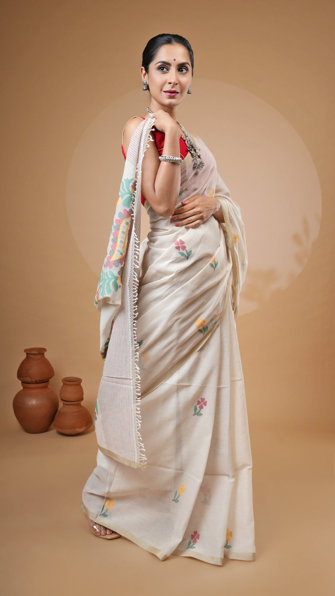 Off-white dhakai saree with multicolour weave in red, green, yellow and black. Flat tassar border and woven butis for a vibrant traditional look.
