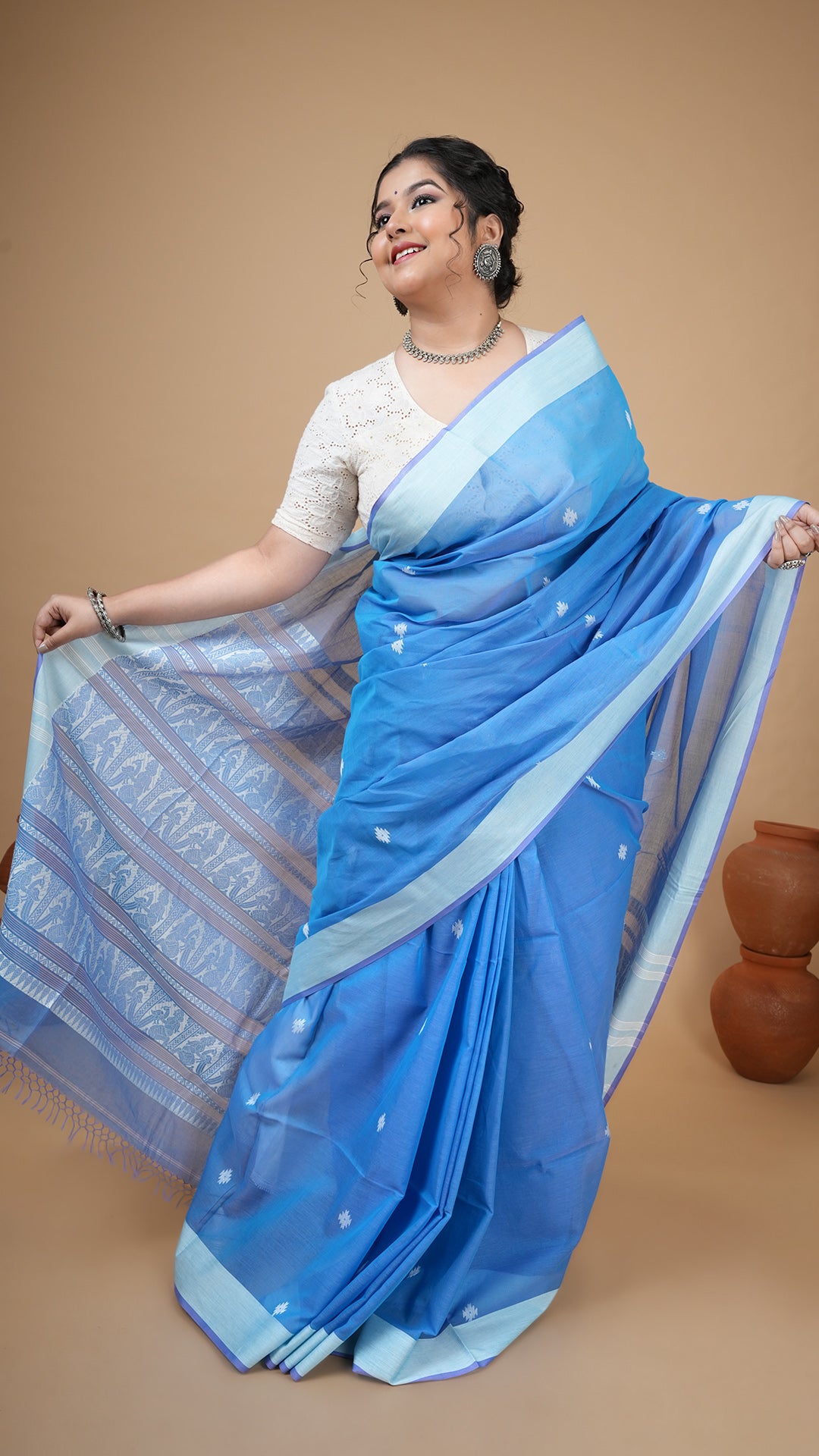 Blue soft cotton tangail saree with white flat border and white woven butis. Baluchari motif pallu ideal for daily or office ethnic wear.
