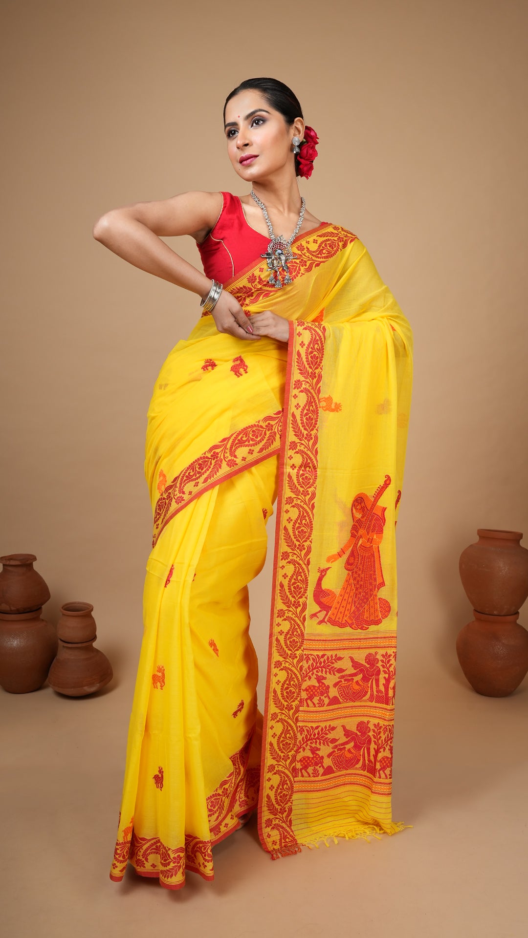 Bright yellow soft cotton tangail saree with red floral border, orange-red figurative pallu and butis. Ideal for puja and gaye holud.