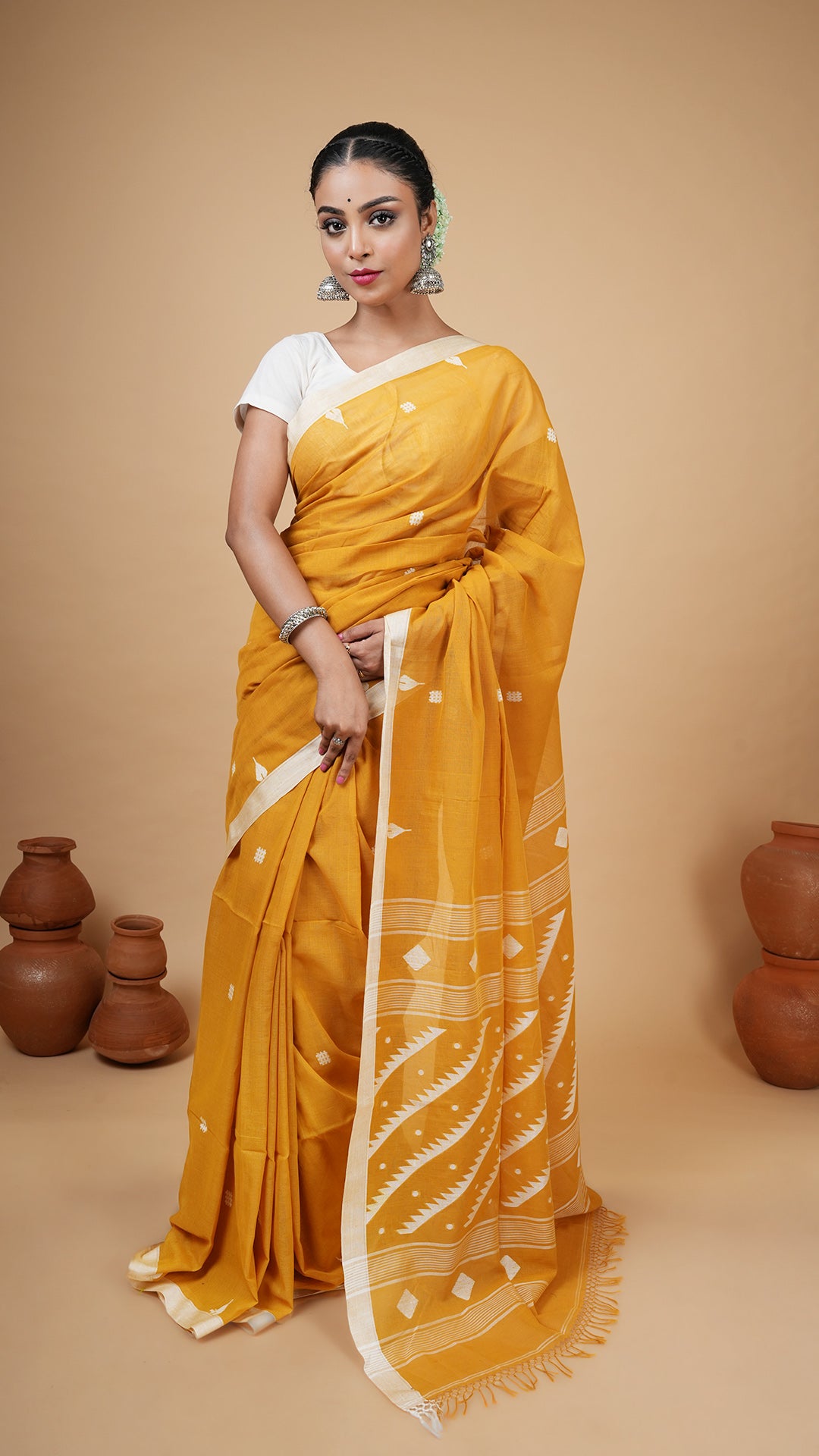 Mustard soft cotton dhakai saree with white woven border, butis, and pallu. Ideal for office or traditional events