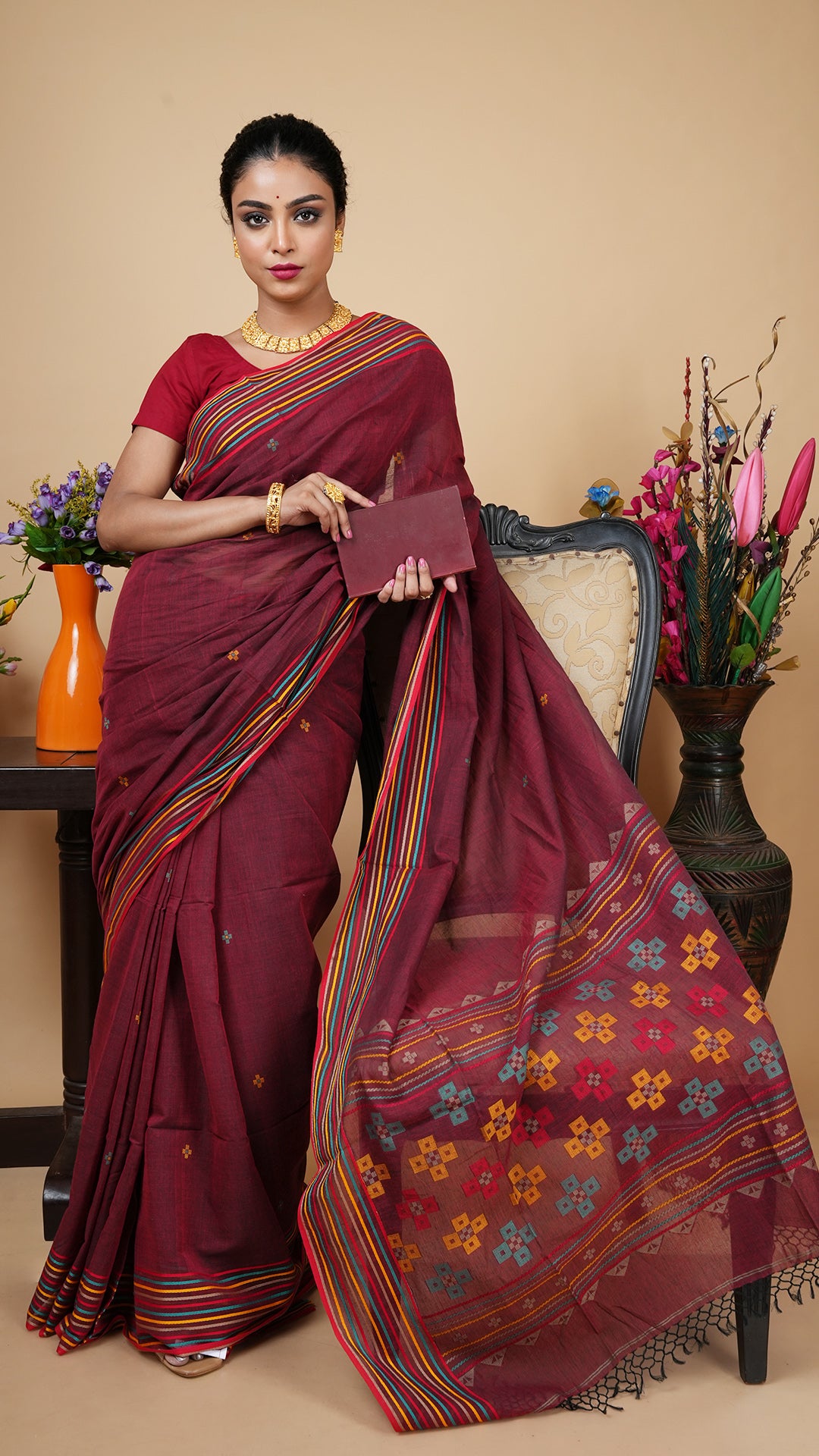 Short maroon Tangail soft cotton saree with striped border in beige, yellow, green, and red. Matching butis and pallu make it perfect for casual, office, or puja wear.