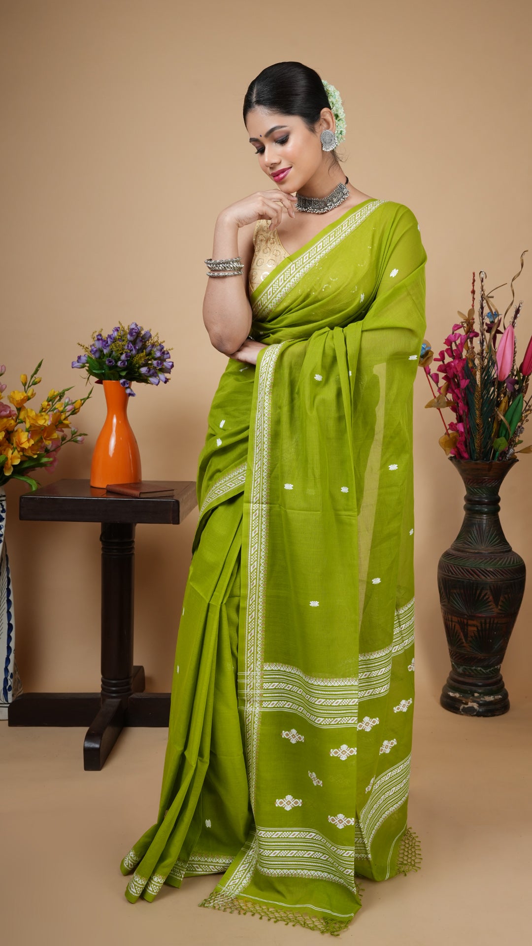 Mehendi green Tangail soft cotton saree with woven white and beige border and pallu, and white butis across the body. Subtle and graceful traditional wear.